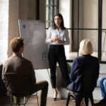 woman with whiteboard lecturing infront of group